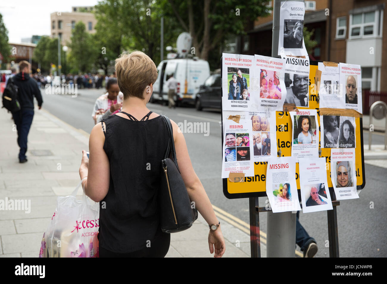 London, UK. 16th June, 2017. A woman glances at missing person notices posted by family members and friends seeking help in tracing those still missing following the fire in the Grenfell Tower close to Latimer Road underground station. Credit: Mark Kerrison/Alamy Live News Stock Photo