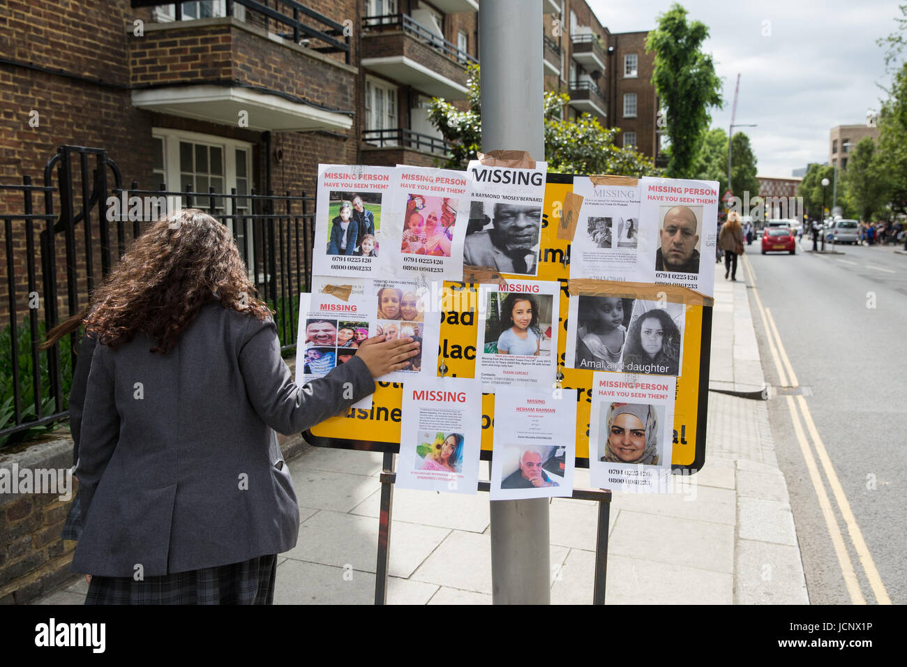 London, UK. 16th June, 2017. A schoolgirl tenderly touches a missing person notice posted by family members and friends seeking help in tracing those still missing following the fire in the Grenfell Tower close to Latimer Road underground station. Credit: Mark Kerrison/Alamy Live News Stock Photo