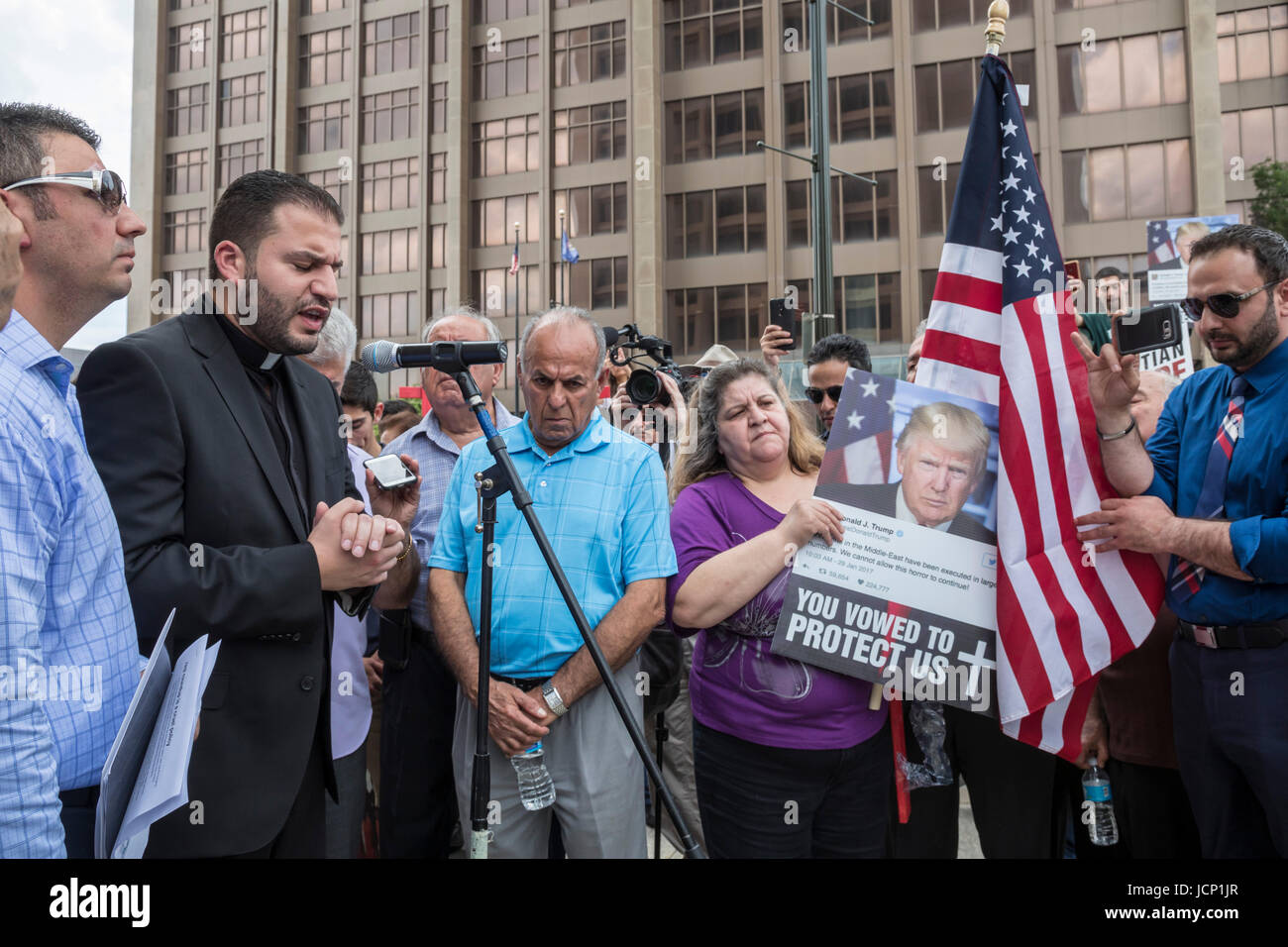 Detroit, Michigan, USA. 16th June, 2017. Members of Detroit's Chaldean community of Iraqi Christians protest the government's arrest of dozens of Iraqis who they plan to deport. Family members say that Iraqi Christians face genocide if they are returned to Iraq. Fr. Anthony Kathawa of St. Thomas Chaldean Catholic Church in West Bloomfield, Michigan, leads a prayer at the end of the rally. Credit: Jim West/Alamy Live News Stock Photo