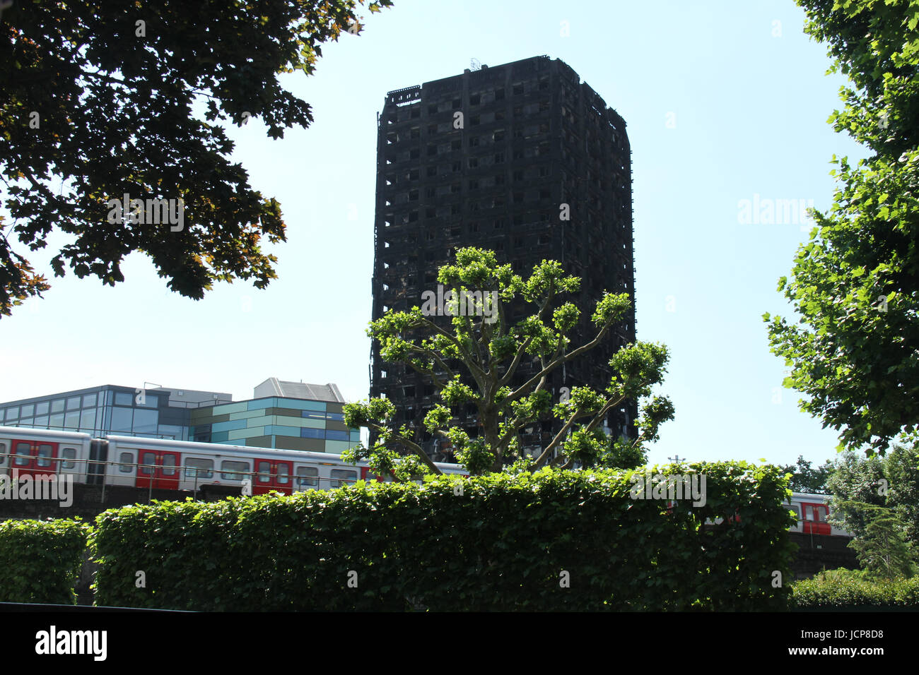 London, UK. 16th June, 2017. A TFL tube train speeds on the tracks below the charred remains of the 24-storey block Grenfell Tower block. At least 30 people have bene confirmed dead with about 70 missing and feared dead. Credit: David Mbiyu/Alamy Live News  Stock Photo