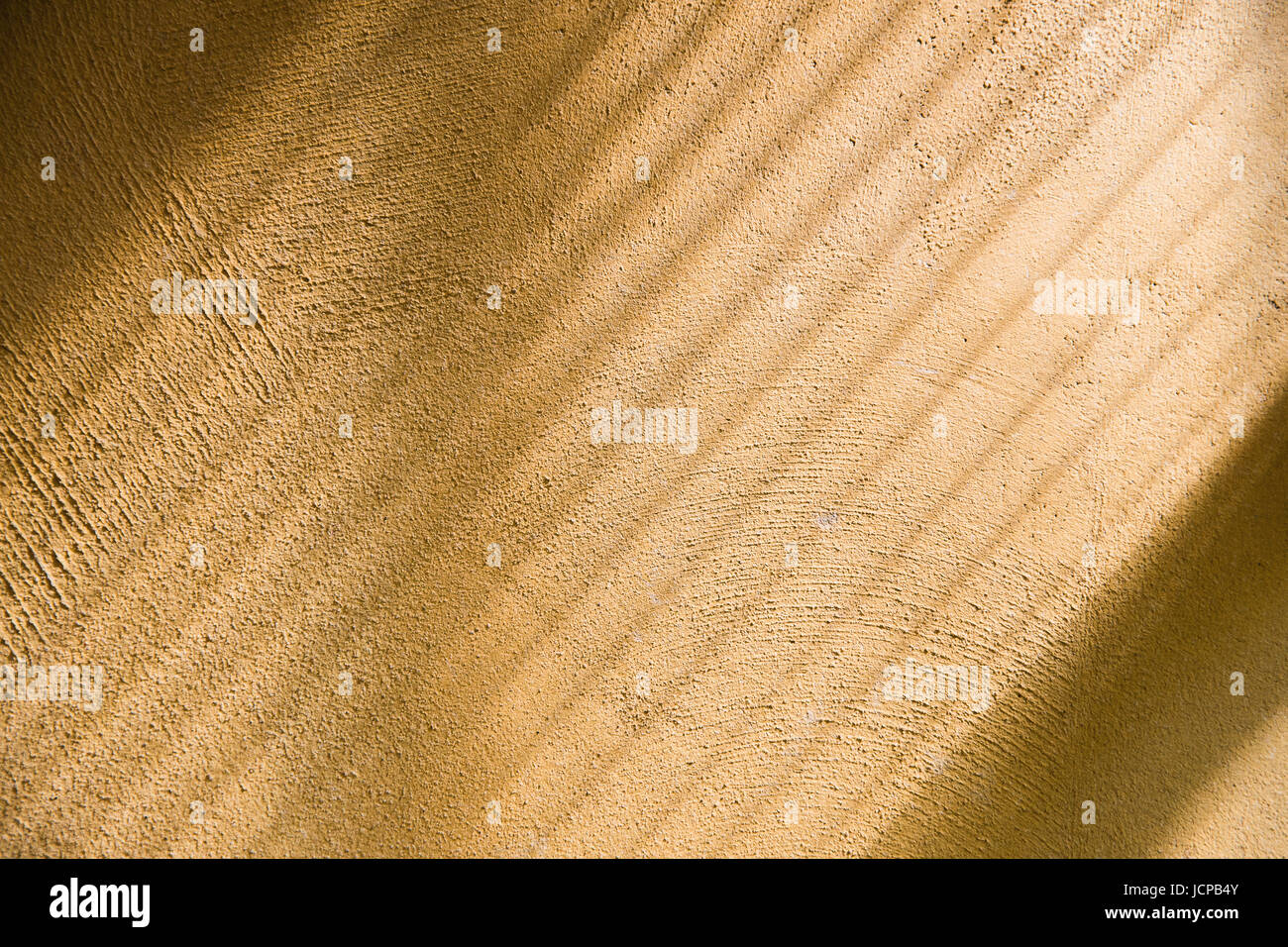 Diagonal shade and light from window curtain onto yellow rough surface wall. Stock Photo