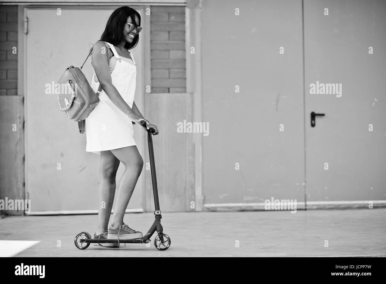 Portrait of a gorgeous african american girl wearing sunglasses with a scooter outside the shopping mall. Stock Photo