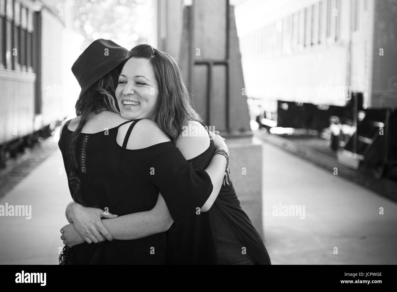 reunited friends hugging at train station Stock Photo