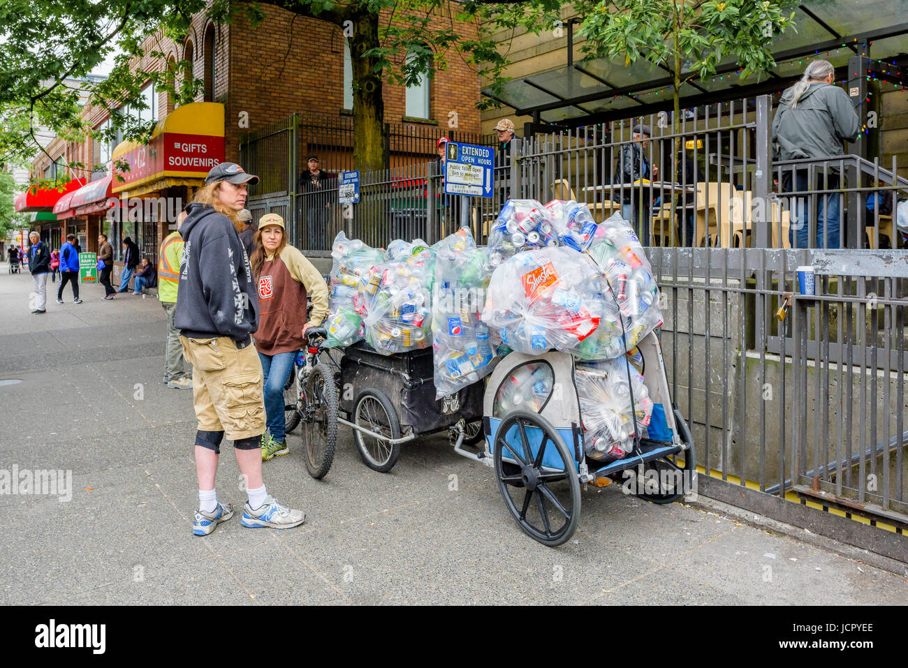 Woman with large load of bottles and cans on bike trailers, DTES, Vancouver, British Columbia, Canada. Stock Photo