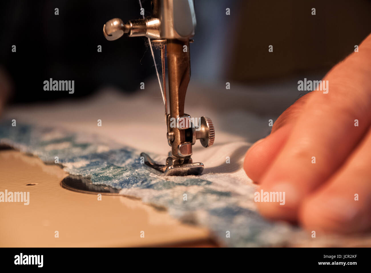 Sewing machine, sewing process, women's hands holding a cloth to sew, connect with another piece