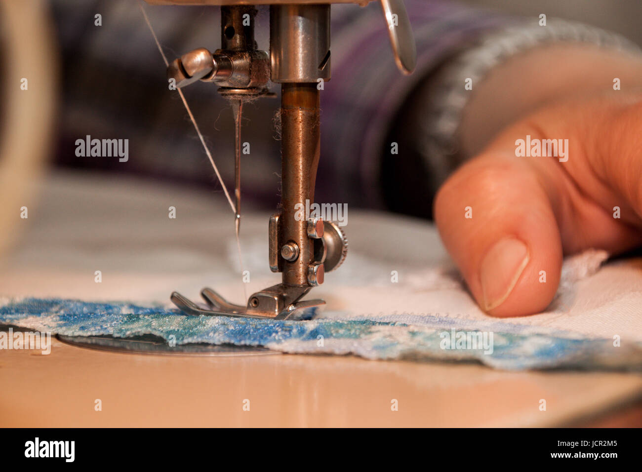 Sewing machine, sewing process, women's hands holding a cloth to sew