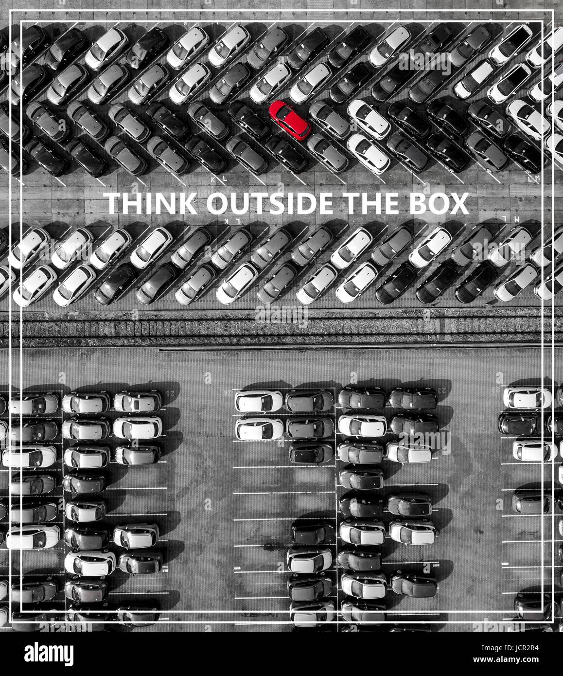 Think outside the box. Many cars one red from above. Stock Photo