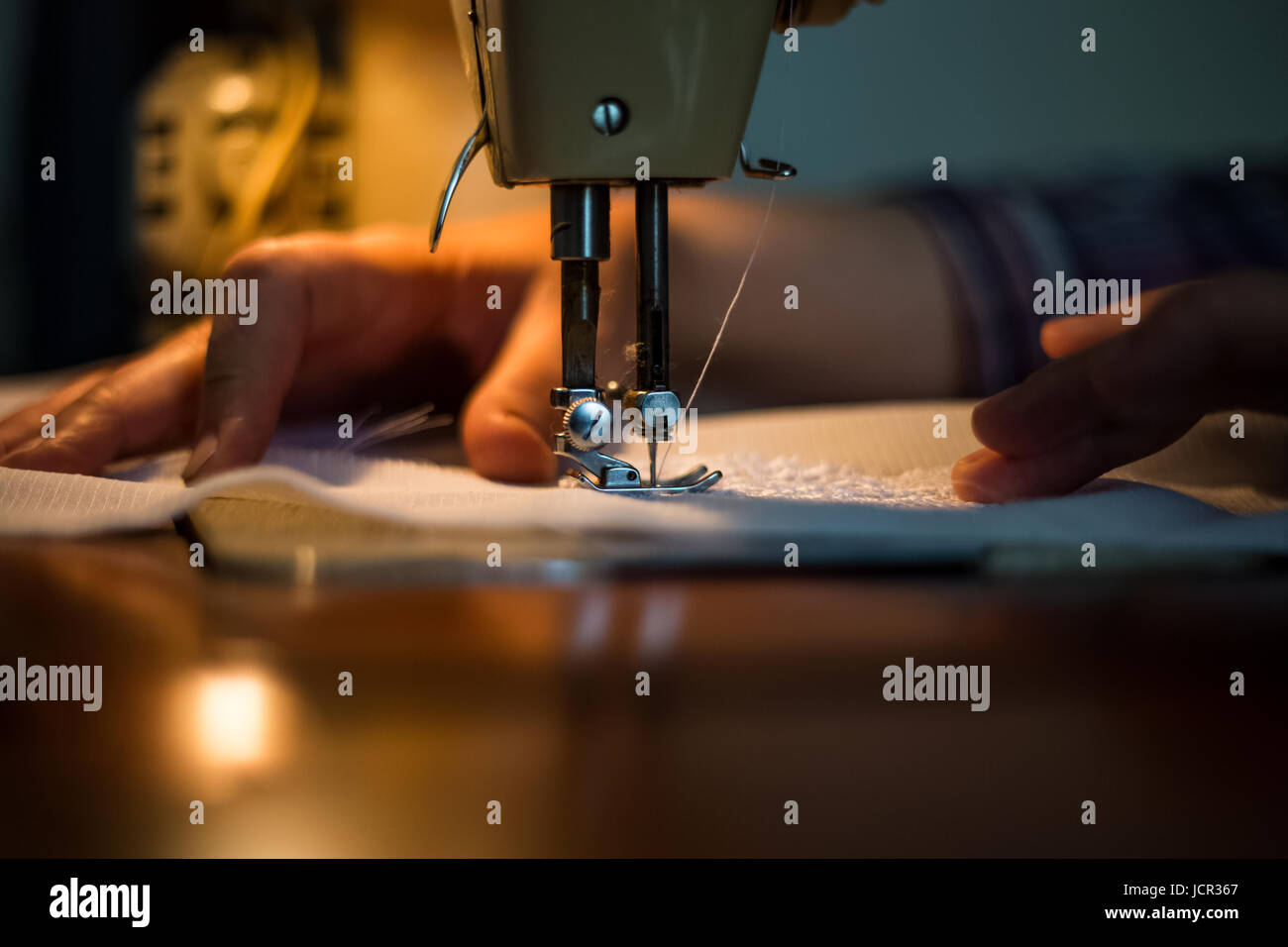 Sewing machine, sewing process, women's hands holding a cloth to sew, connect with another piece