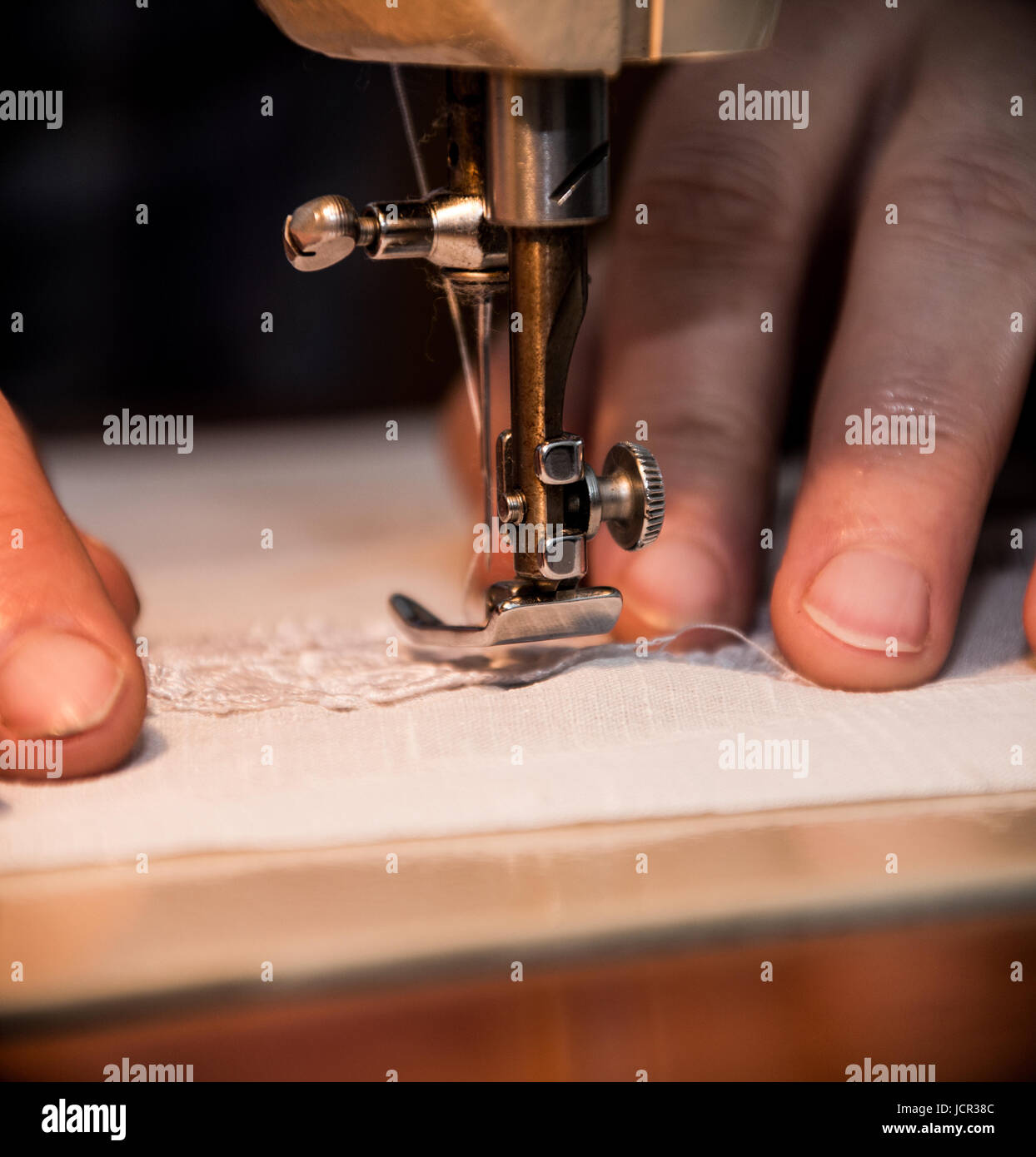 Sewing machine, sewing process, women's hands holding a cloth to sew