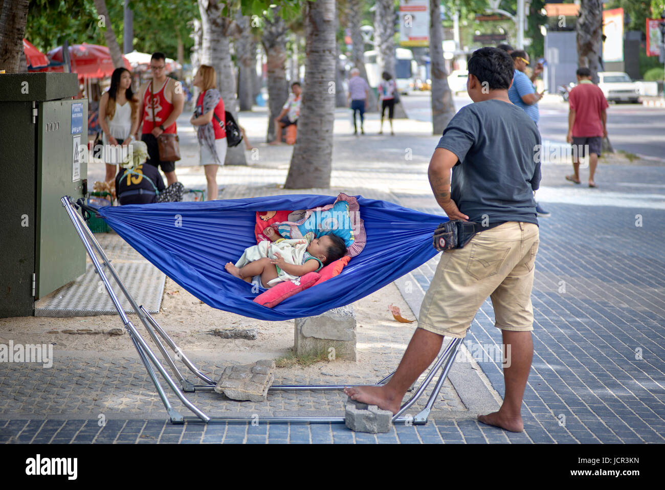 Fatherhood funny. Father rocking sleeping bay in a hammock. Thailand Southeast Asia Stock Photo