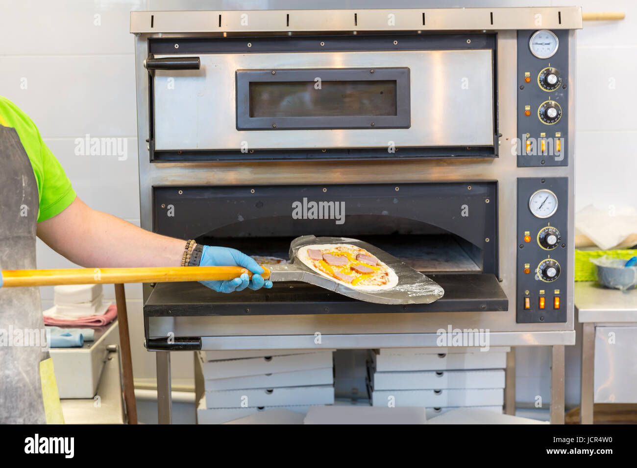Baker hands with shovel, cooking pizza, electric ovens Stock Photo