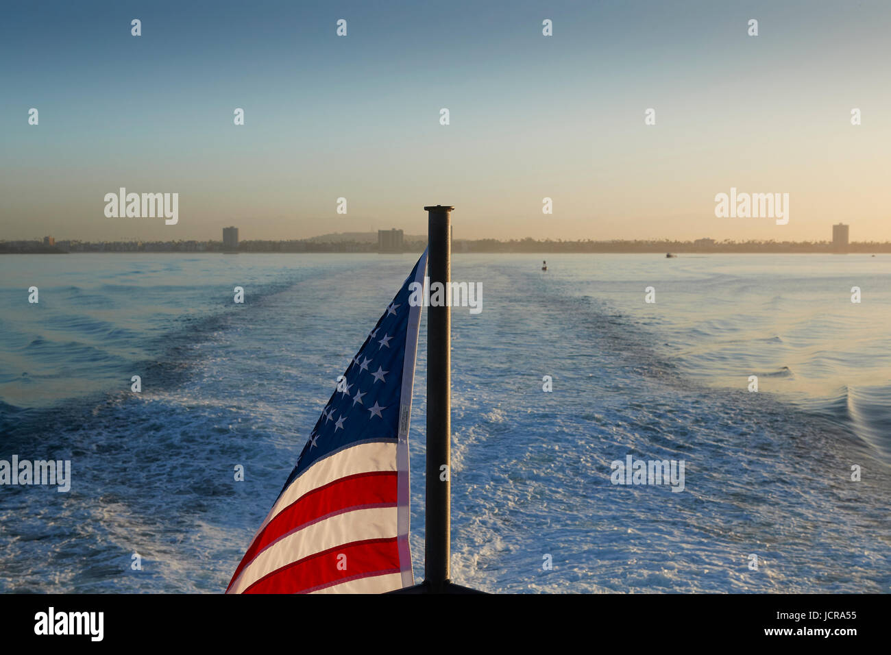 Stars And Stripes Flag Flying From The Stern Of A Catalina Express SeaCat Speeding Out Of Long Beach Harbor, California. Stock Photo