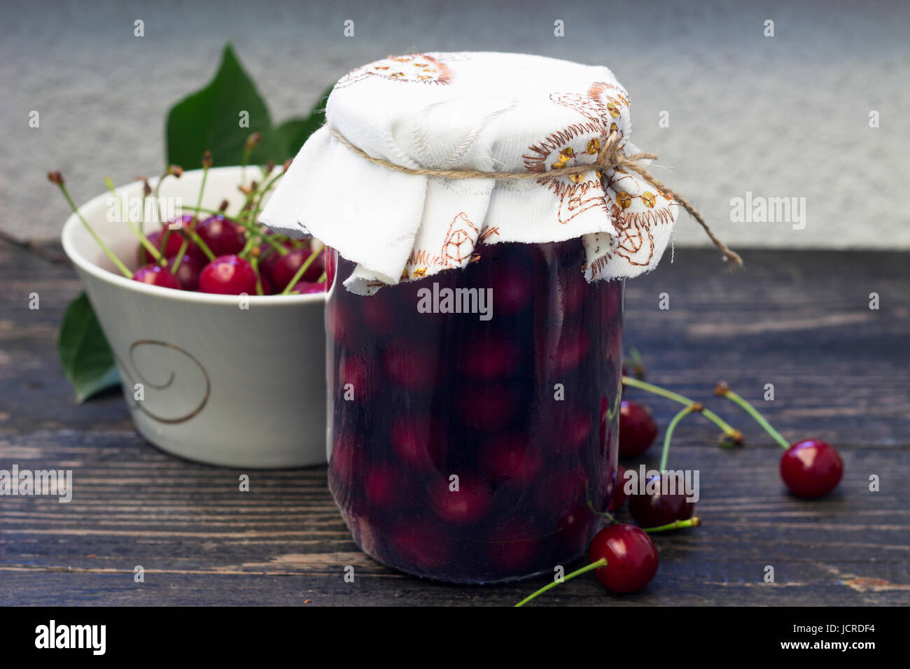 Jar with sour cherry compote on the wooden table Stock Photo