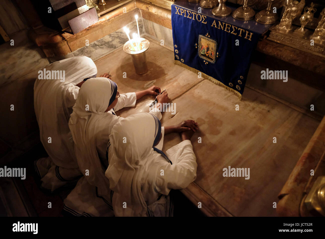 Roman Catholic nuns belonging to Mother Teresa's Missionaries of Charity in Calcutta, praying inside the renovated Aedicula the14th Station of the cross traditionally believed to be the site of the crucifixion and tomb of Jesus Christ inside the Church of Holy Sepulchre in the Christian Quarter old city East Jerusalem Israel Stock Photo