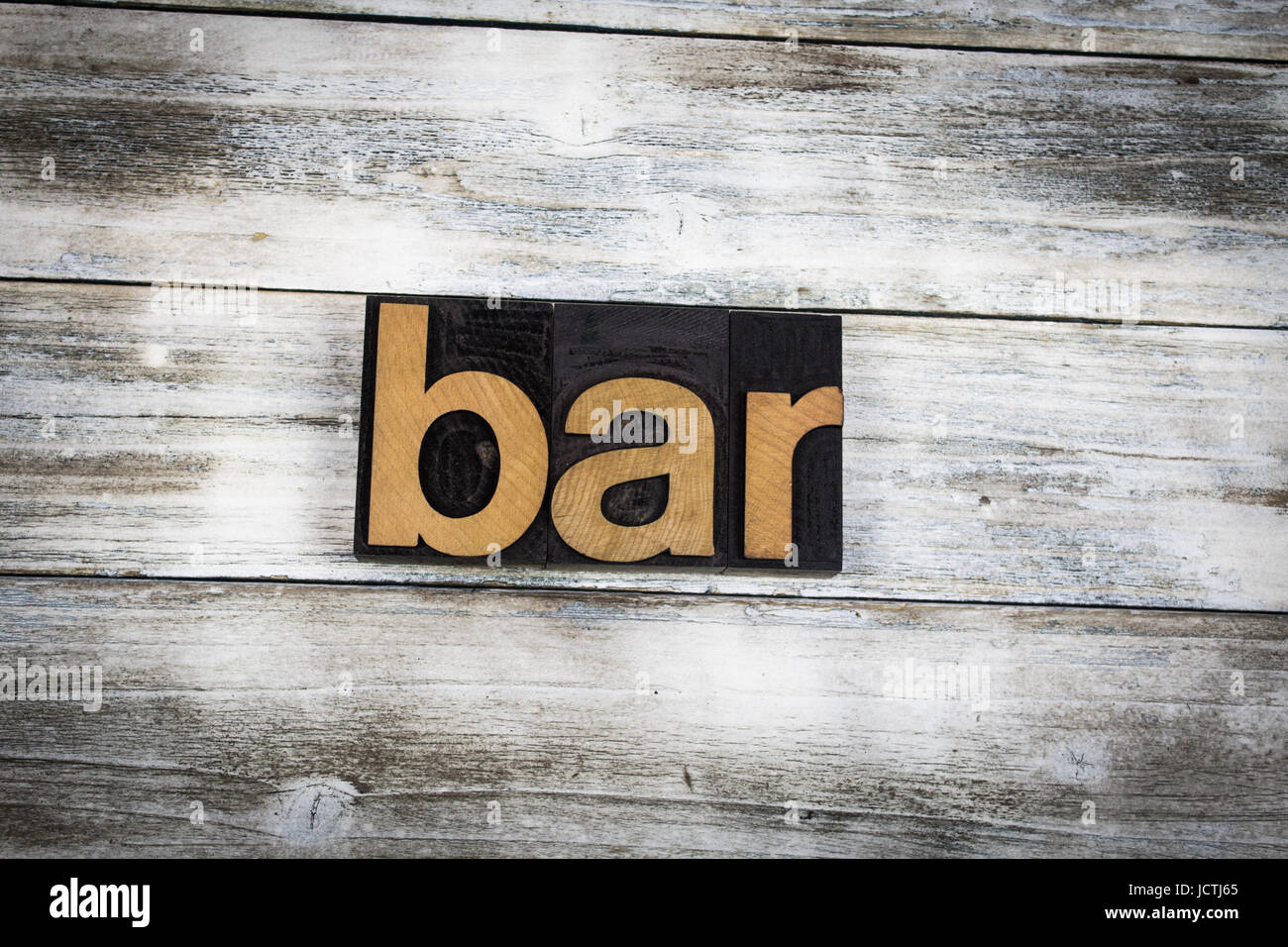 The word "bar" written in wooden letterpress type on a white washed old