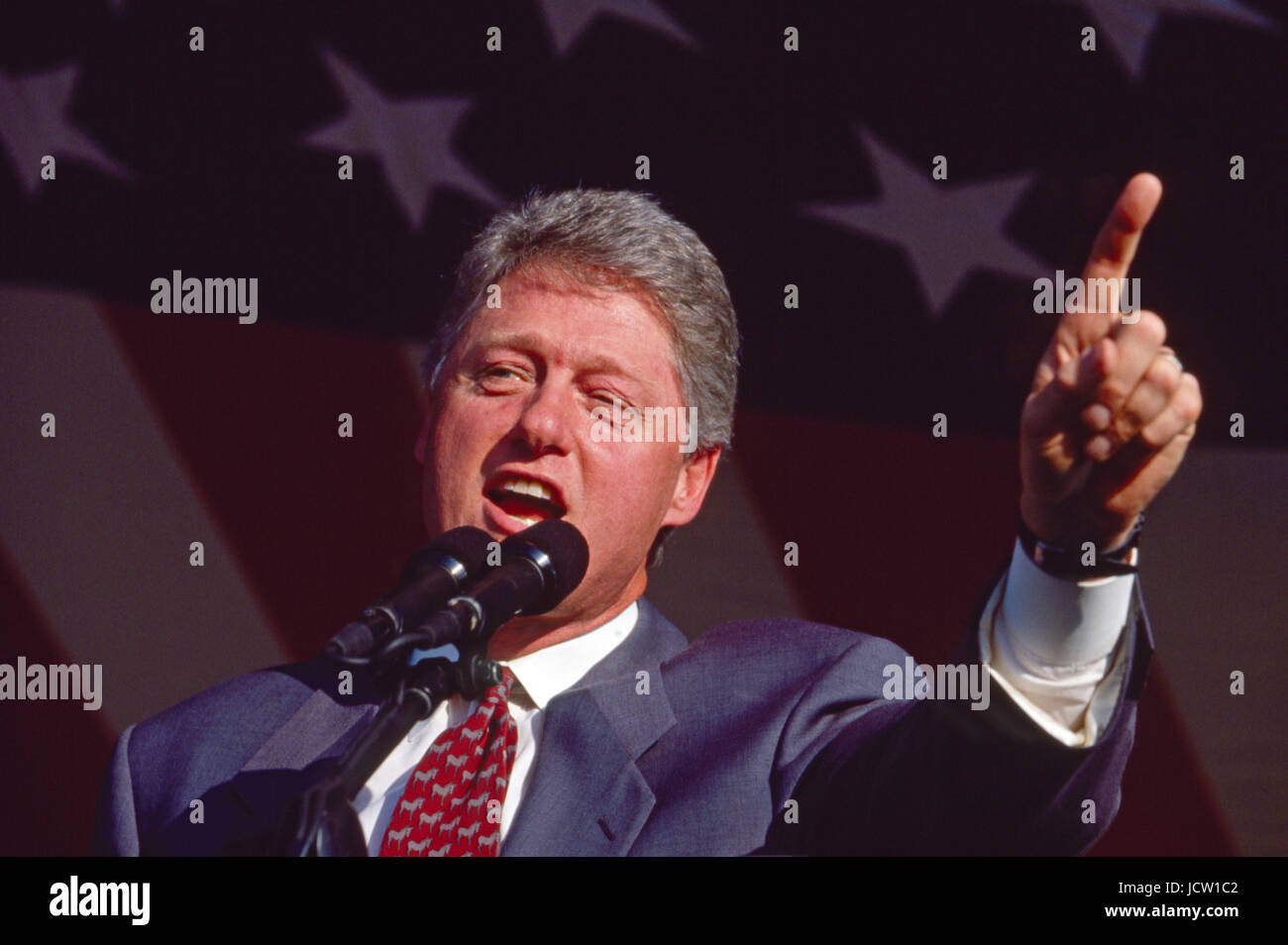 President Bill Clinton speaks under a giant American flag. Stock Photo