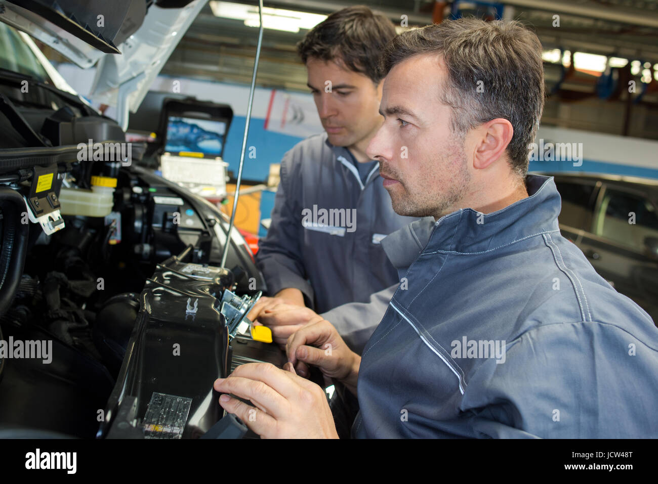 car mechanic and assistant in garage Stock Photo - Alamy