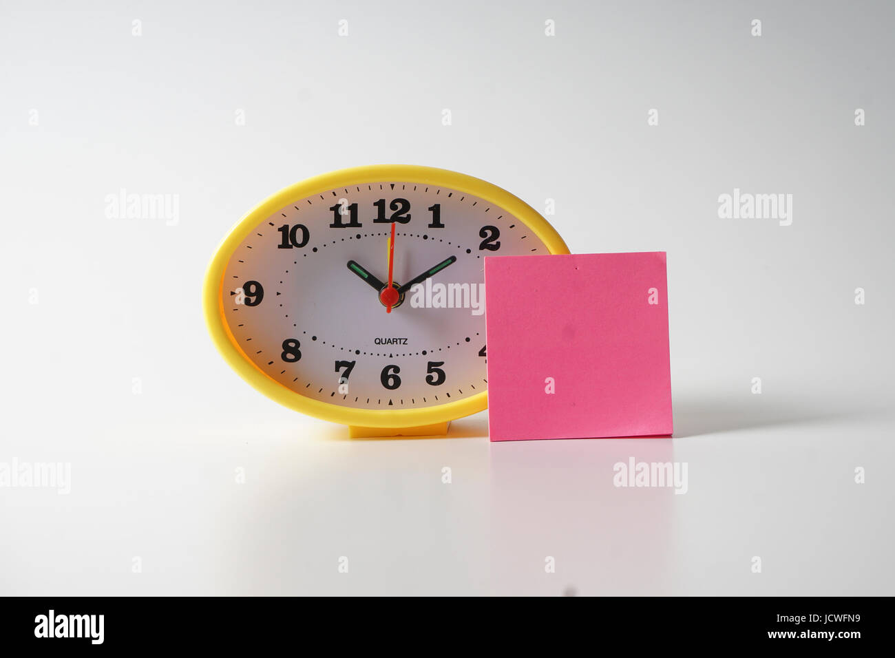 Yellow table clock with time management conceptual text on the note
