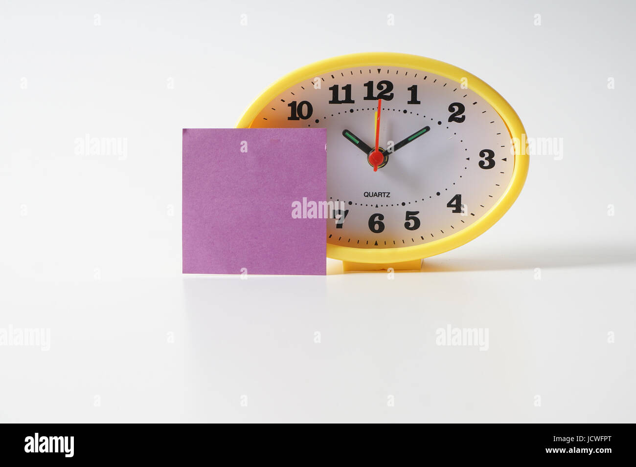 Yellow table clock with time management conceptual text on the note
