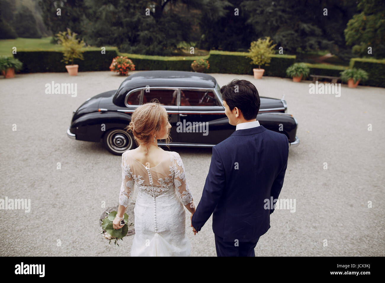 bride and groom standing in the yard near the car Stock Photo - Alamy