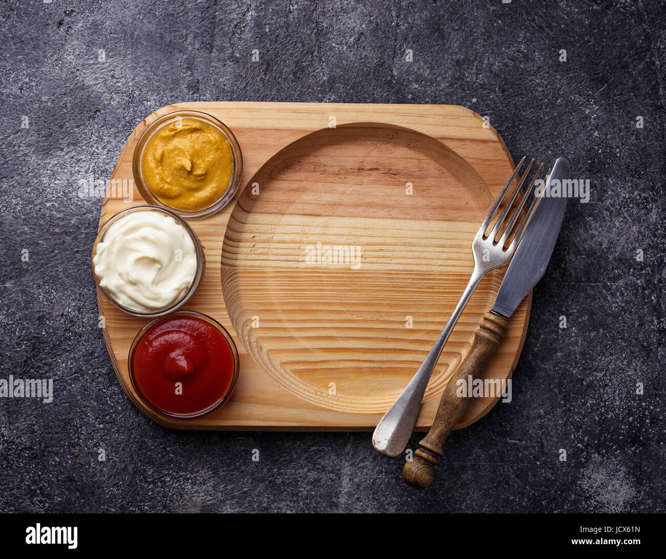 Food background with mustard, ketchup, mayonnaise, fork and knife
