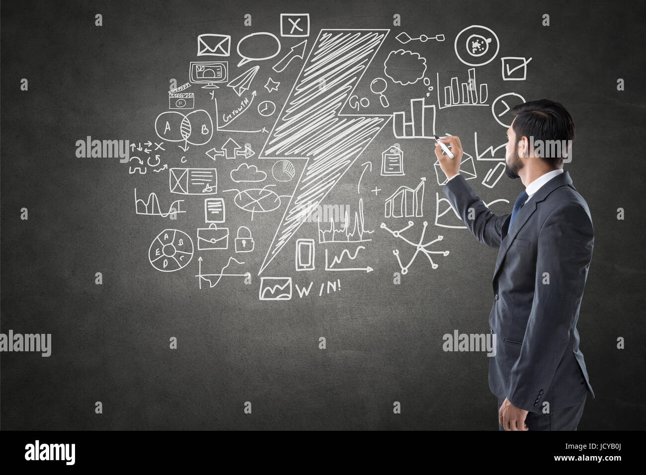 Businessman drawing icons on blackboard Stock Photo