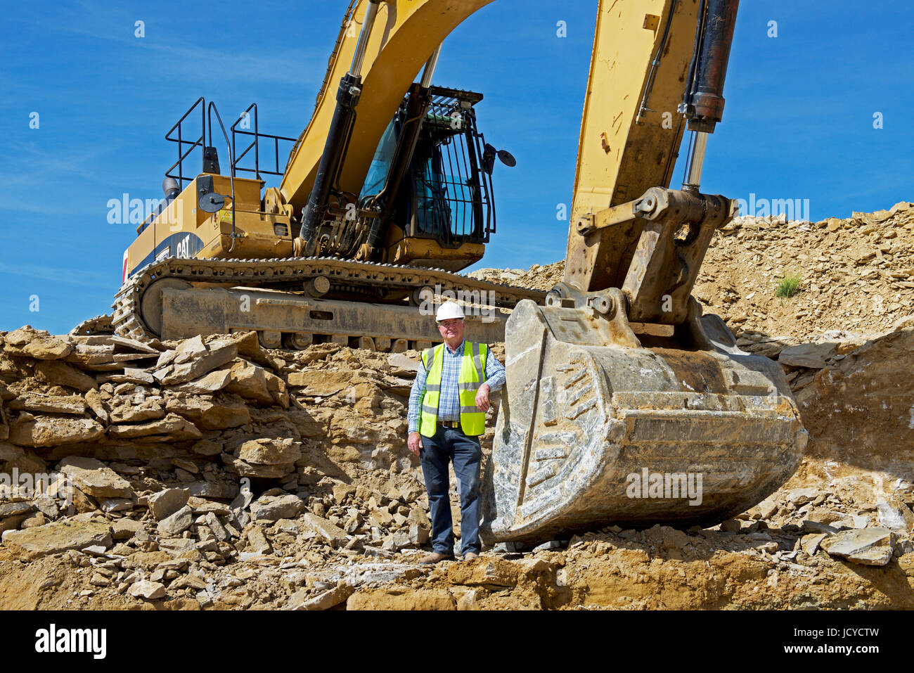 Man standing next to JCB digger at Tinkers Barn Stone Quarry, Guiting
