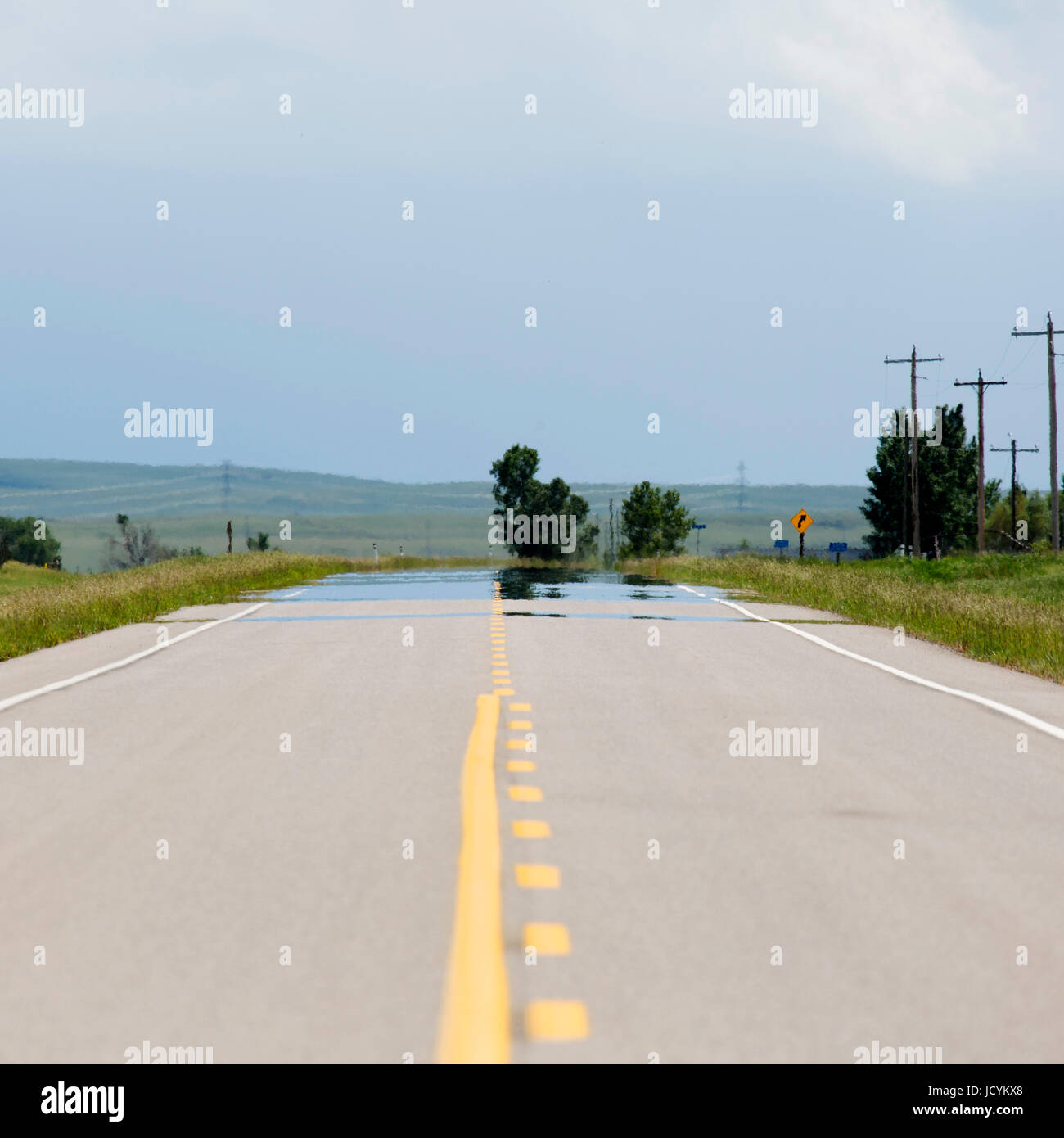 Empty road in Alberta, Canada. The tarmac on the highway has yellow lane markings. Stock Photo
