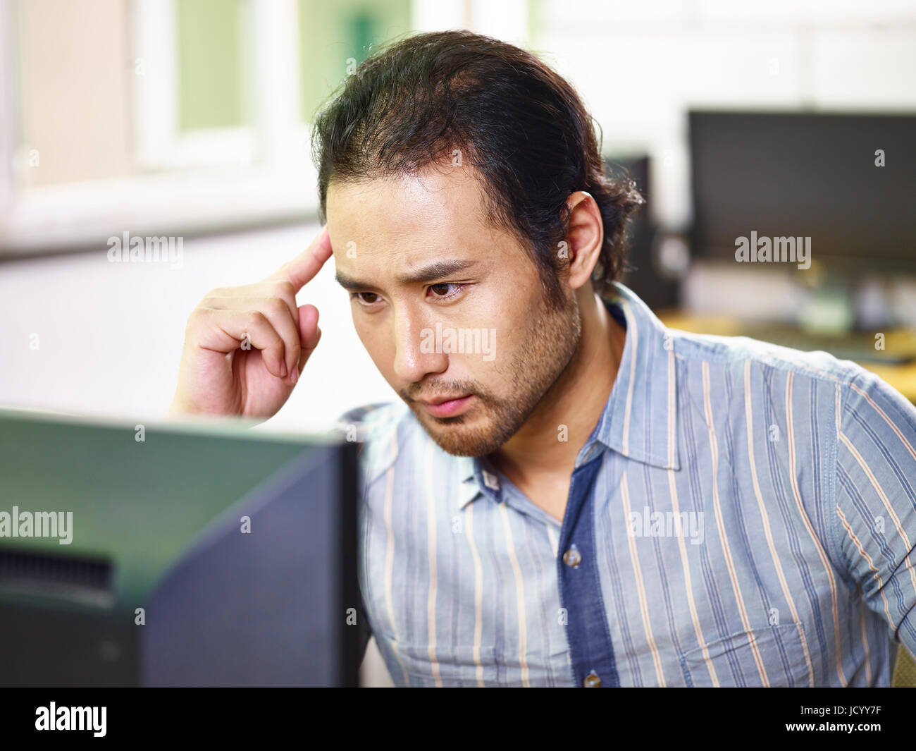 asian businessman working in office using computer thinking hard. Stock Photo