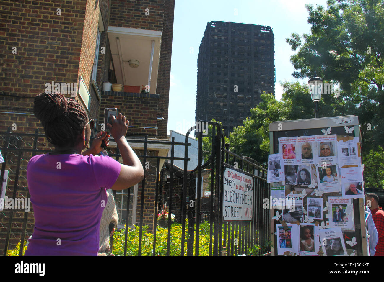 London, UK. 16th June, 2017. A woman takes photos of the charred remains of the 24-storey block Grenfell tower block. At least 30 people have bene confirmed dead with about 70 missing and feared dead. Credit: David Mbiyu/Alamy Live News  Stock Photo