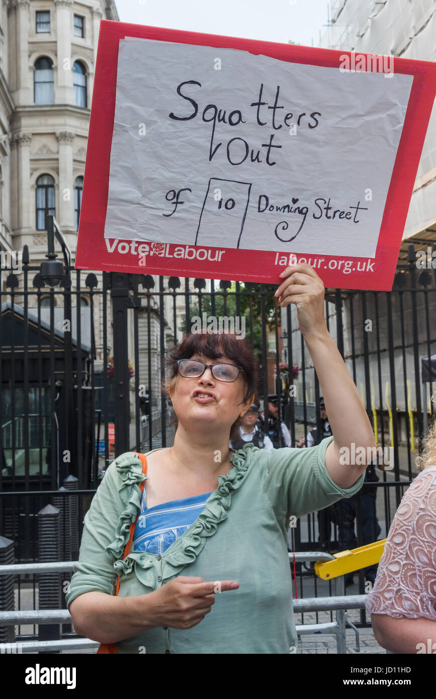 June 17, 2017 - London, UK - London, UK. 17th June, 2017. A woamn holds up a poster 'Squatters Out of 10 Downing St' at the protest at Downing St calling on Theresa May to resign. Mostly made up of vocal supporters of Jeremy Corbyn, buoyed up by the election results which showed him to be eminently electable, there were speeches by Labour MPs Marsha De Cordova who gained Battersea from the Conservatives, Rupa Huq who greatly increased her tiny majority and Shadow Education Secretary Angela Rayner. There were others who spoke about the DUP, as a party intrinsically linked with Protestant terror Stock Photo