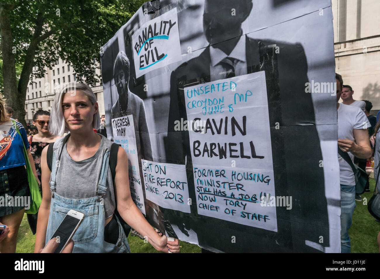 London, UK. 17th June, 2017. London, UK. 17th June, 2017. A woman stands with a large placard titled 'THe Banality of Evil' shoing Theresa May and former Croydon MP Gavin Barwell, now Tory Chief of Staff, who sat on the fire report by the coroner in 2013 at the protest at Downing St calling on Theresa May to resign. Peter Marshall Images Live Credit: Peter Marshall/ImagesLive/ZUMA Wire/Alamy Live News Stock Photo