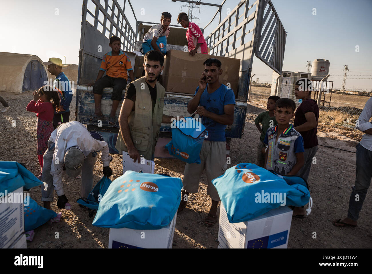 Tikrit, Iraq. 16th June, 2017. Members of Muslim Aid hand out food and hygiene supplies at an aid distribution point in the Shahama I Camp, near Tikrit, Iraq, 16 June 2017. Iraqi forces have routinely rounded up the families of suspected Islamic State (IS) fighters in liberated territory, detaining them for an unspecified amount of time. Shahama I Camp is the only camp in Iraq that specifically only detains relatives of suspected Islamic State members. They are not allowed to leave the walled premise. Photo: Andrea DiCenzo/dpa/Alamy Live News Stock Photo