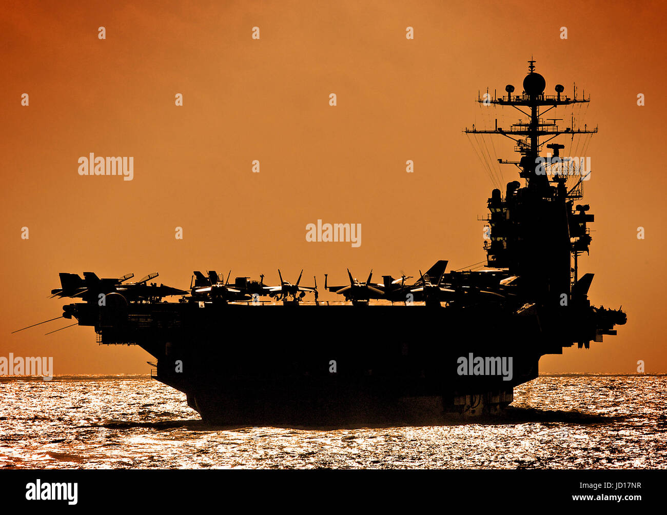 The Nimitz-class aircraft carrier USS George Washington against an orange sky. U.S. Navy photo by Photographer's Mate Airman Michael D. Blackwell II Stock Photo