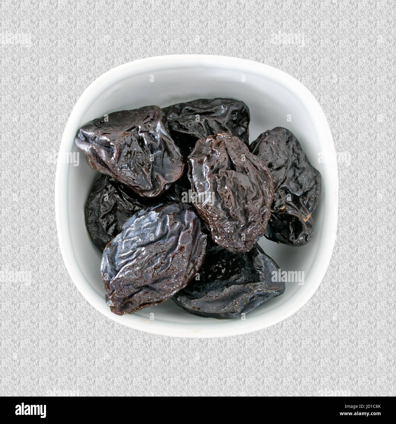 Dried prunes in bowl. High in roughage, iron and boron. Stock Photo