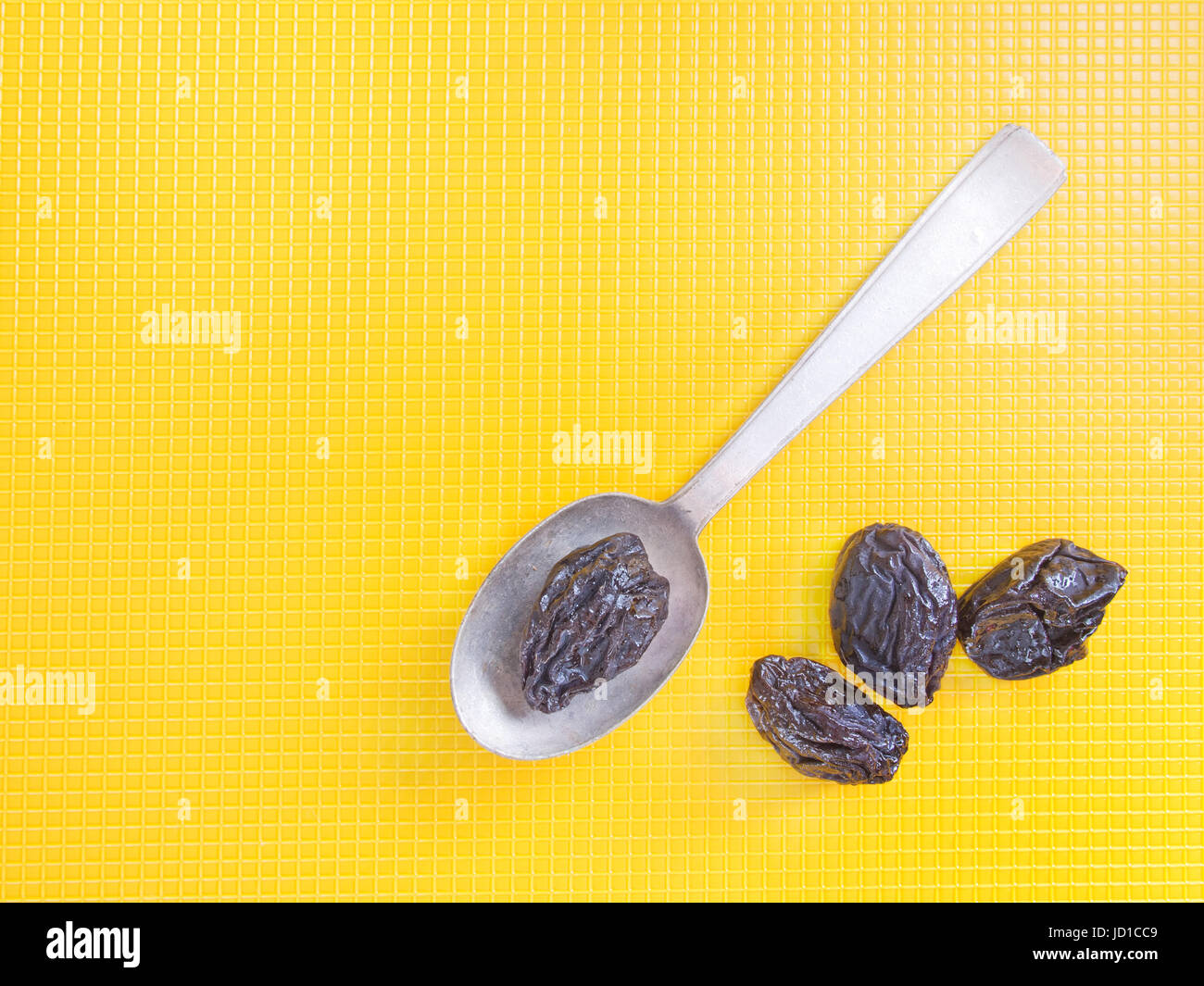 Dried prunes on yellow. Natural laxative. Stock Photo