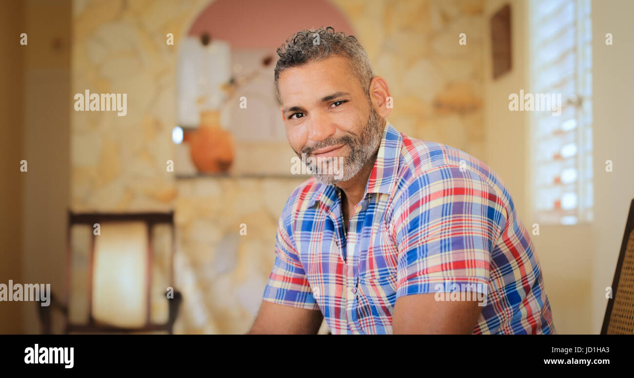 Portrait of homosexual adult man. Happy hispanic gay smiling at camera, sitting on sofa at home. Stock Photo