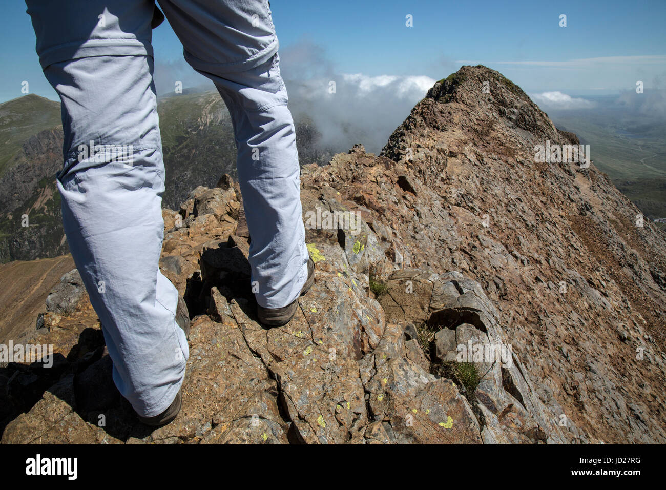 Legs of a hiker about to cross Crib Goch, or Red Ridge, a knife edge arete in the Snowdonia National Park in North wales. Stock Photo