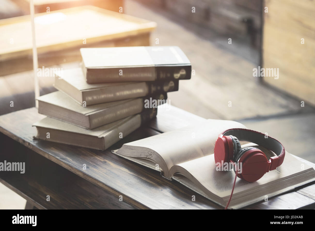 Red headphone on book in cafe or library,morning light. Stock Photo