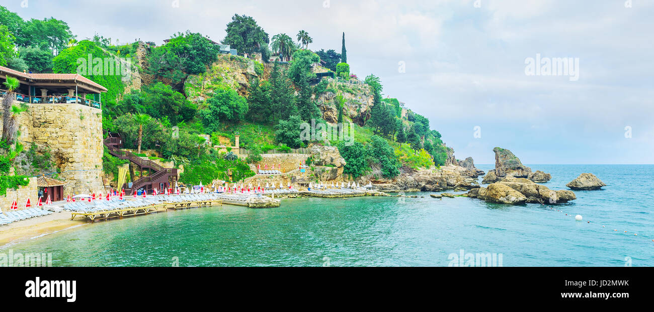 The Mermerli beach in Kaleici district is the picturesque cosy sand beach, located at the foot of the rocky cliff, covered with greenery, Antalya, Tur Stock Photo