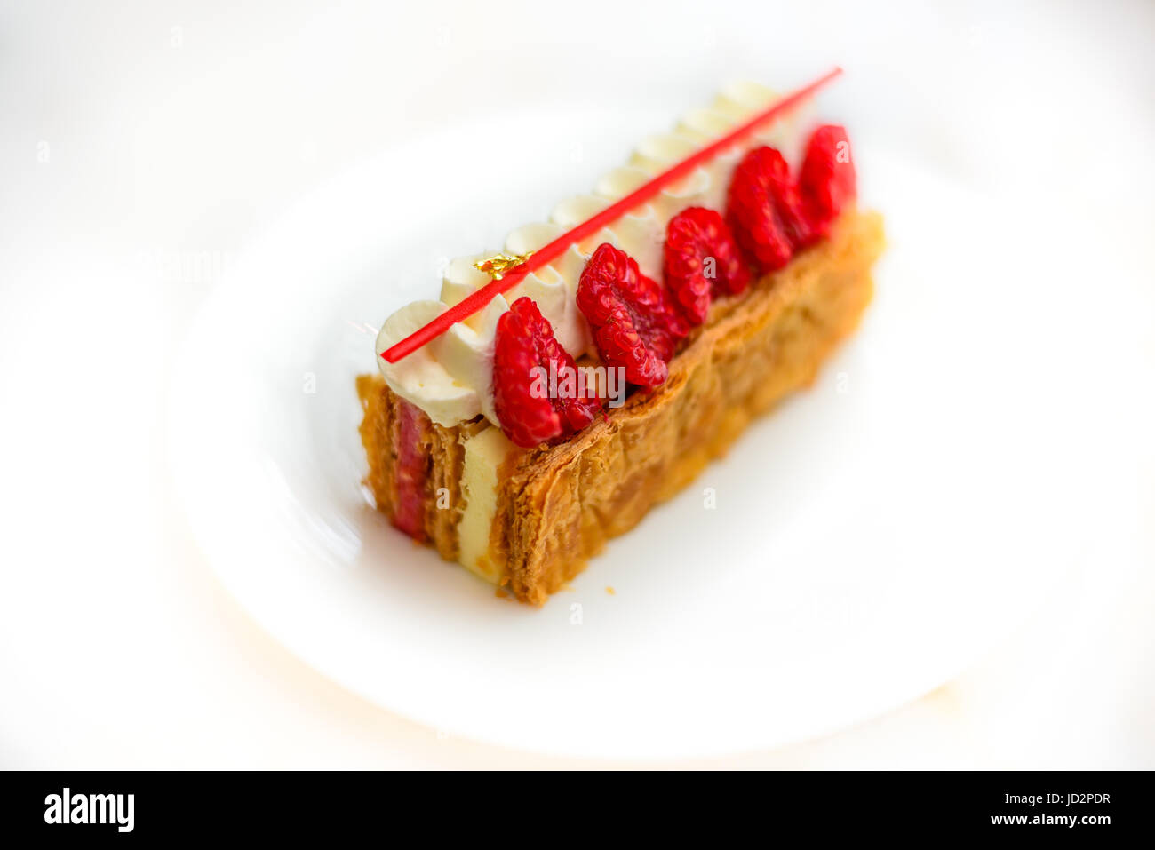 Vanilla and Raspberry Mille feuille pastry cake on white china plate Stock Photo