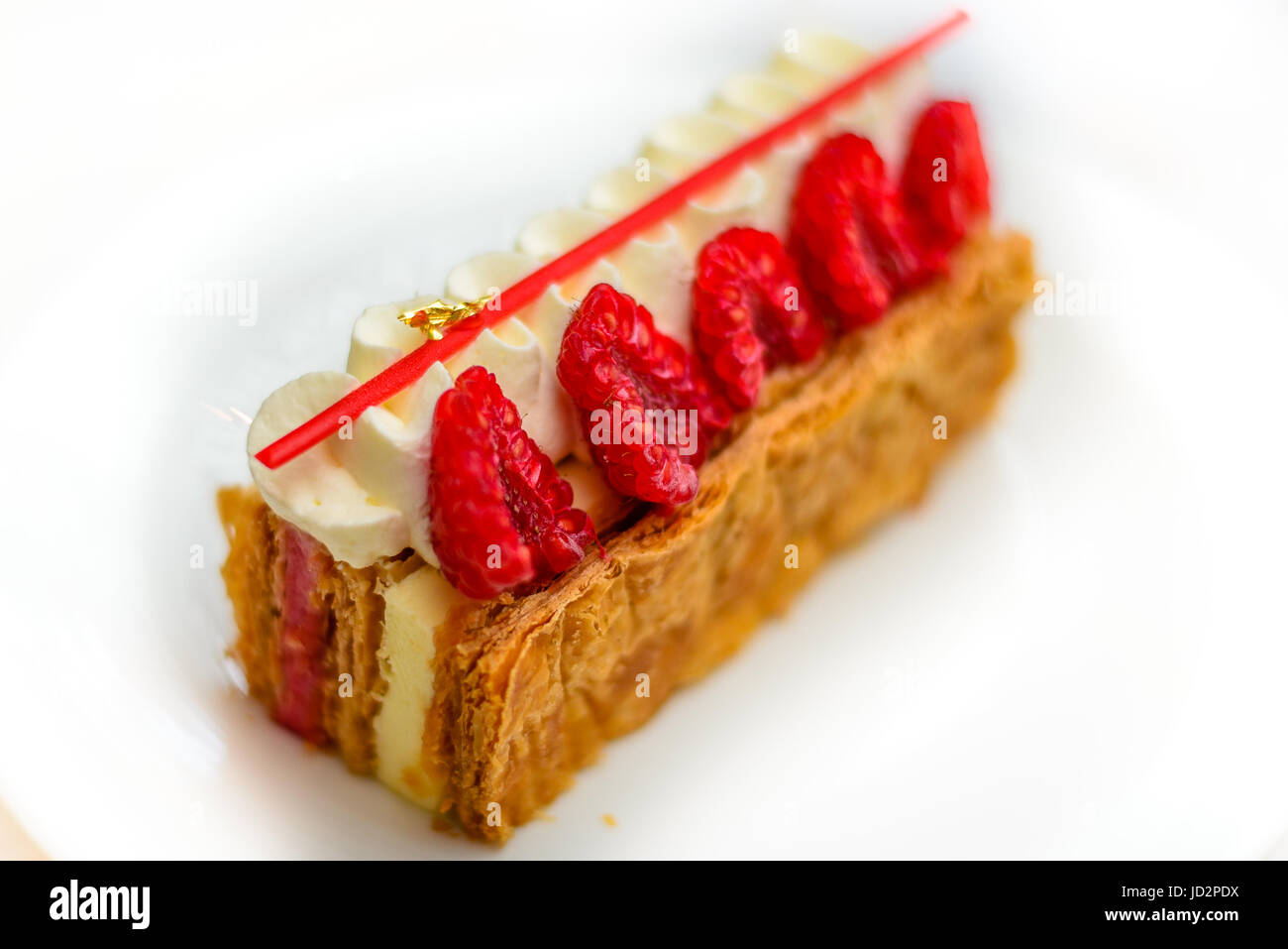Vanilla and Raspberry Mille feuille pastry cake on white china plate Stock Photo