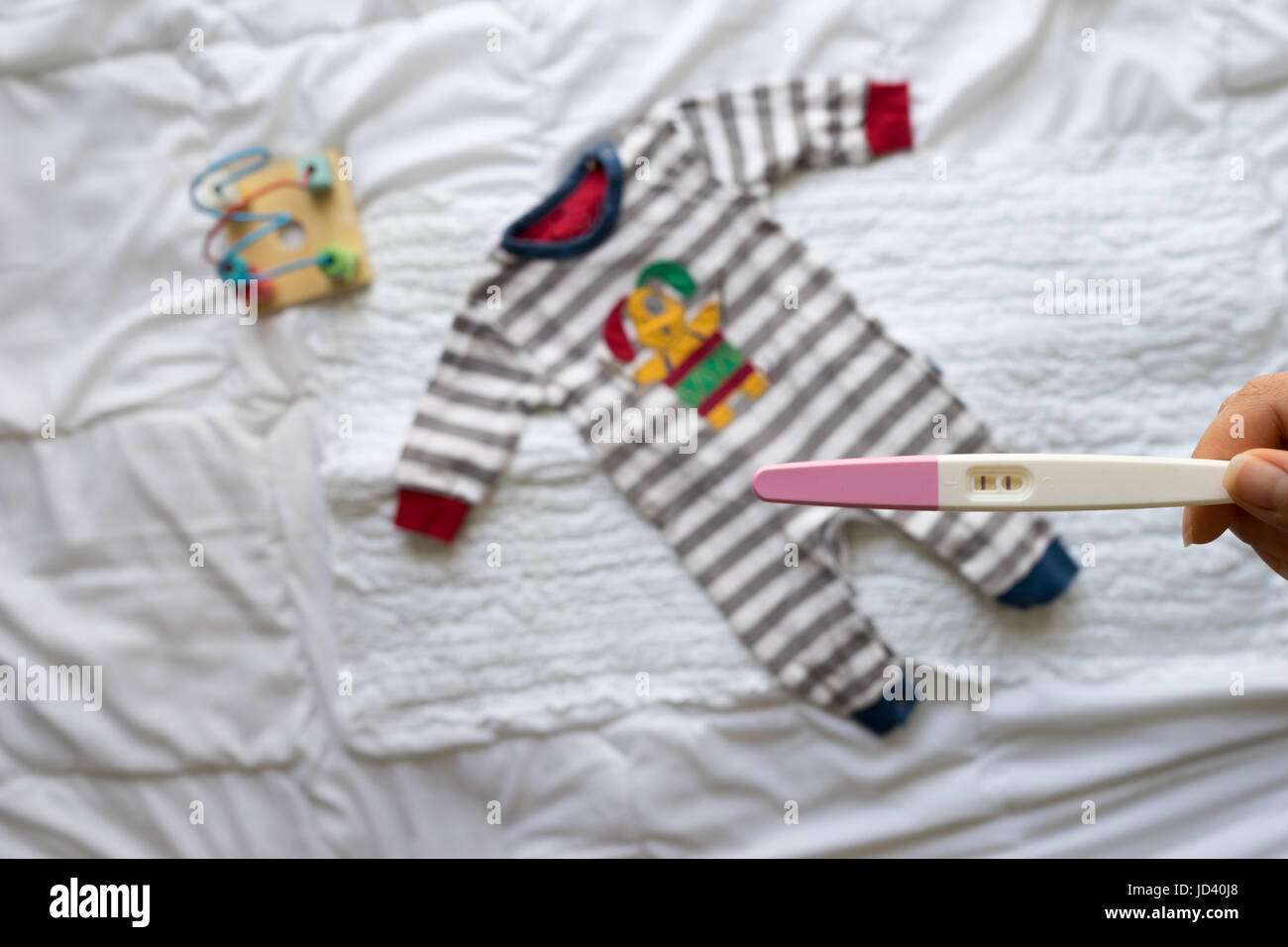 Positive Pregnancy Test In Woman Hand And Baby Clothes On White Background Stock Photo Alamy
