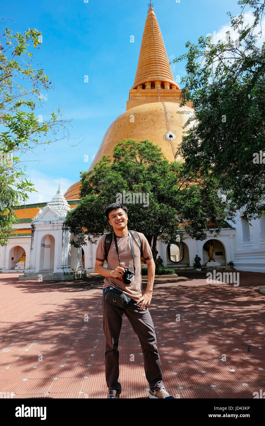 Tourist man with camera standing in front og thai pagoda temple. Stock Photo