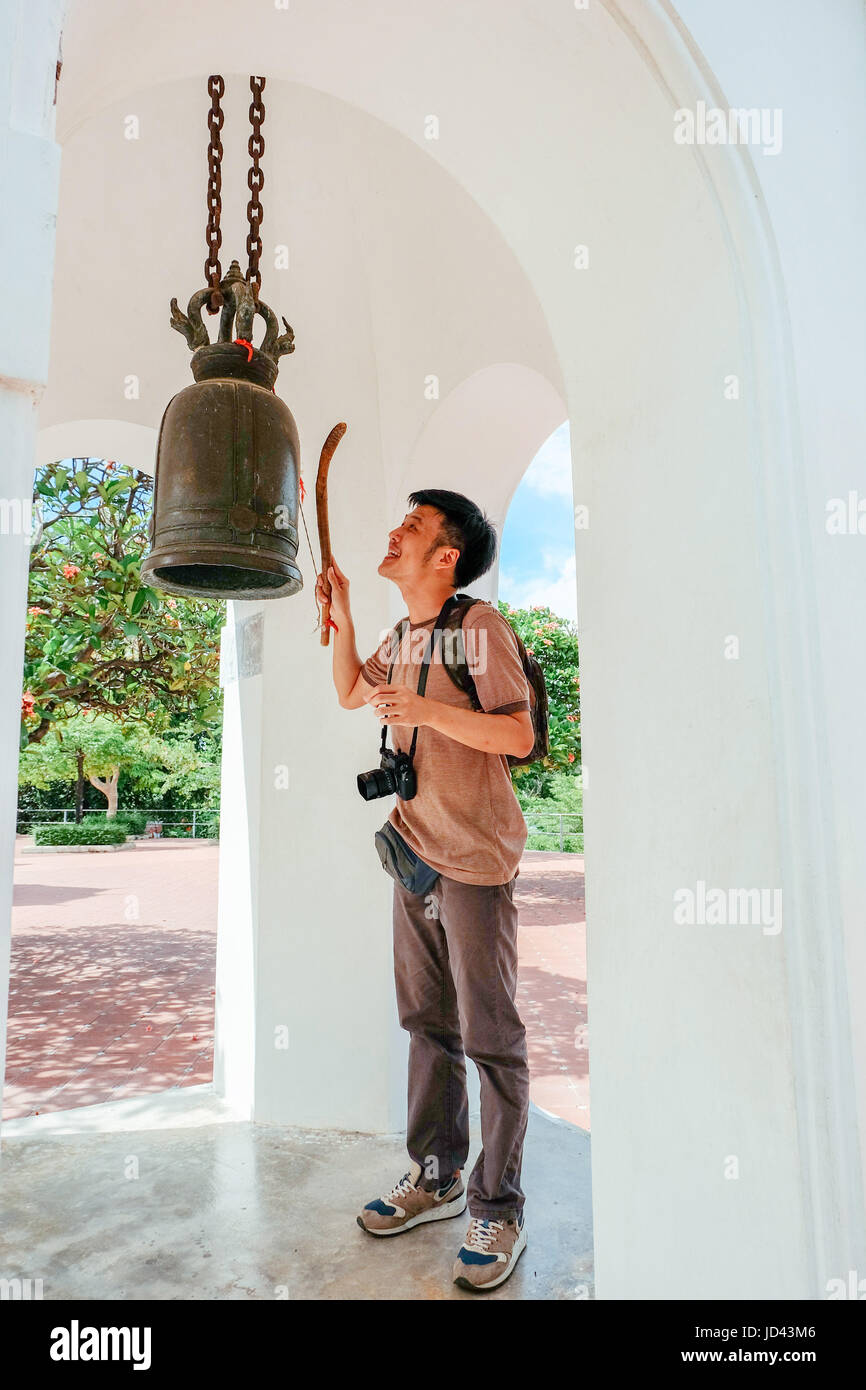 Tourist man knock the metal bell in thai temple. Stock Photo