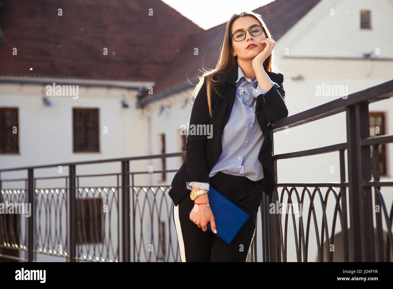 Young fashionably dressed businesswoman with notebook posing in the city Stock Photo