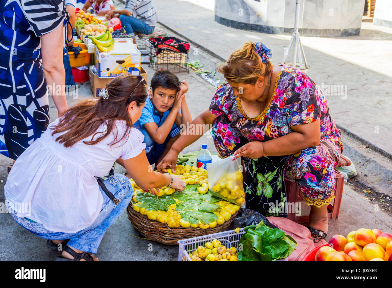 SAMARKAND, UZBEKISTAN - AUGUST 28: Woman picking ripe yellow figs out of the basket at Siab bazaar, local market in Samarkand. August 2016 Stock Photo