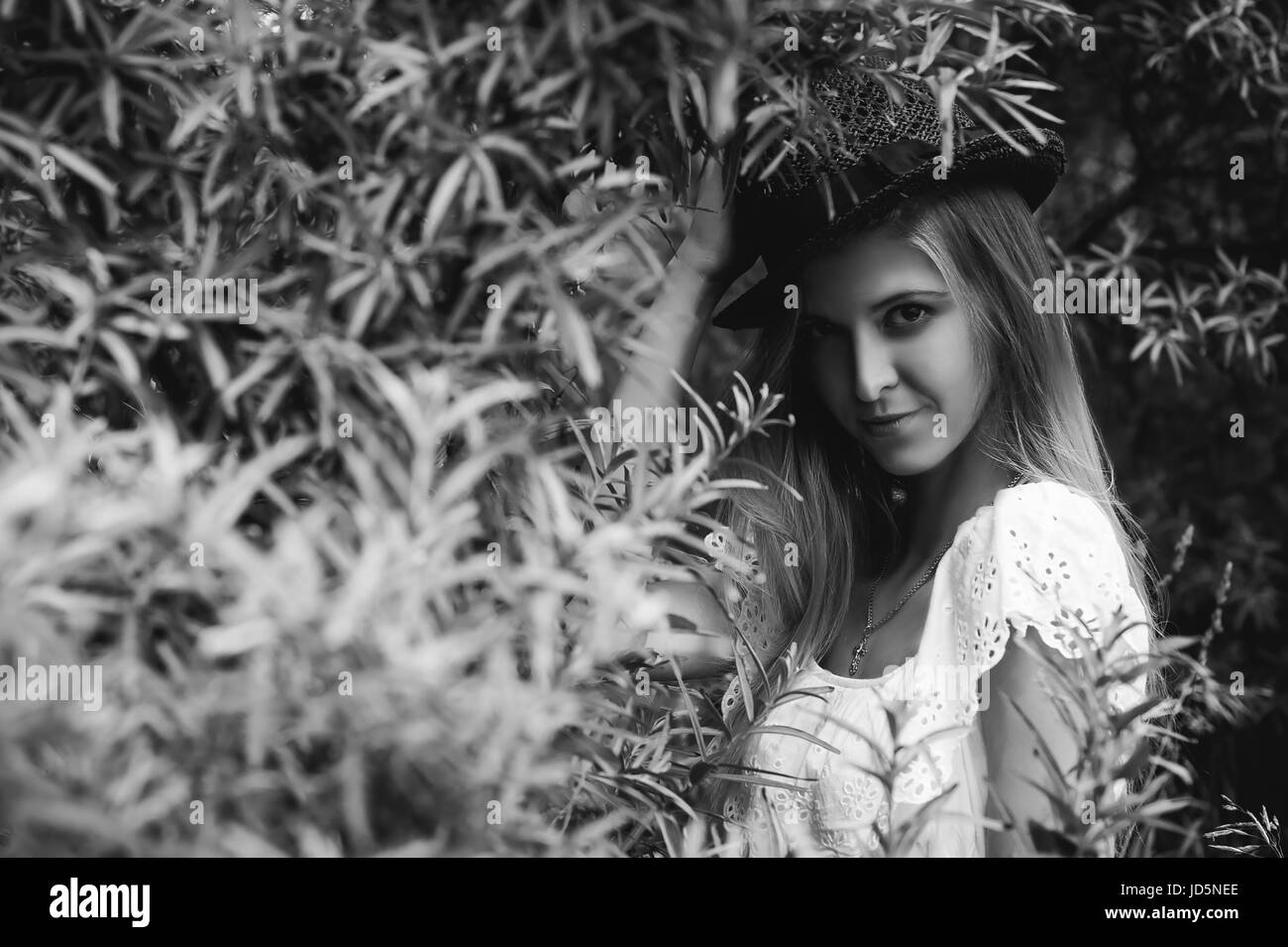 Black and white portrait of a young woman with a hat in bushes Stock ...