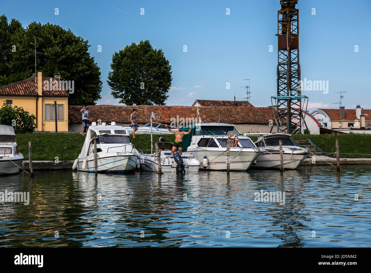 Boats moored at the dock with people preparing to sail in Caorle - Italy Stock Photo