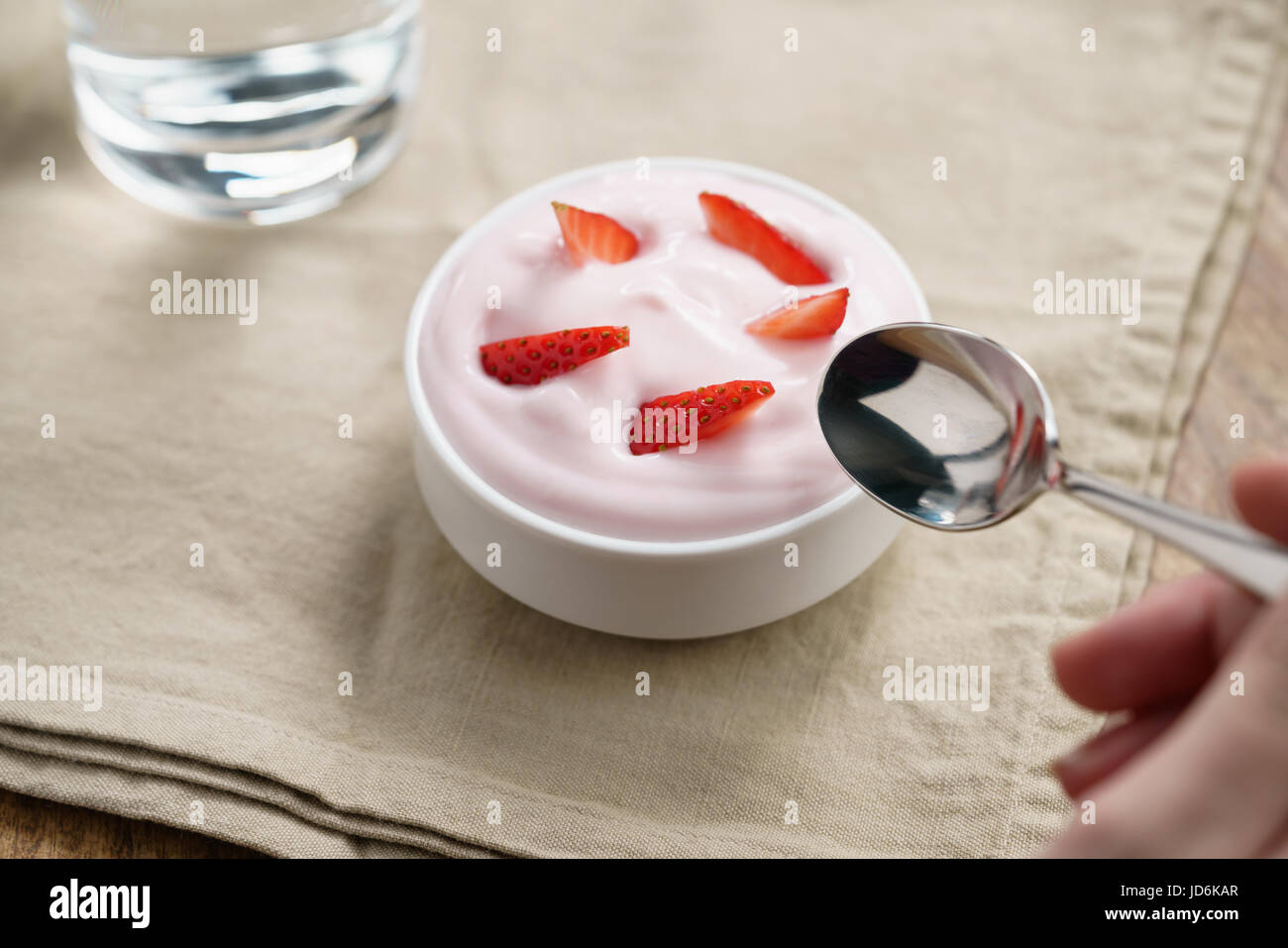 pov teen girl hand eating organic strawberry yogurt Stock Photo